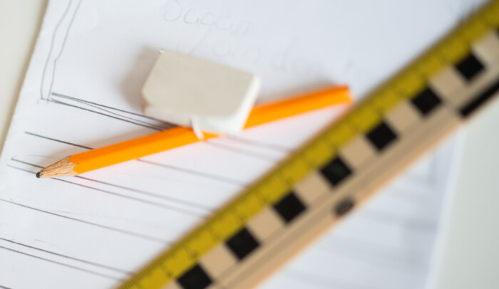 Linjal, sudd och en penna ligger placerade på ett pappersblock